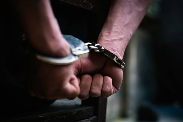 Man on the chair in Handcuffs. Rear view and Closeup ,Men criminal in handcuffs arrested for crimes. With hands in back,boy  prison shackle in the jail violence concept.